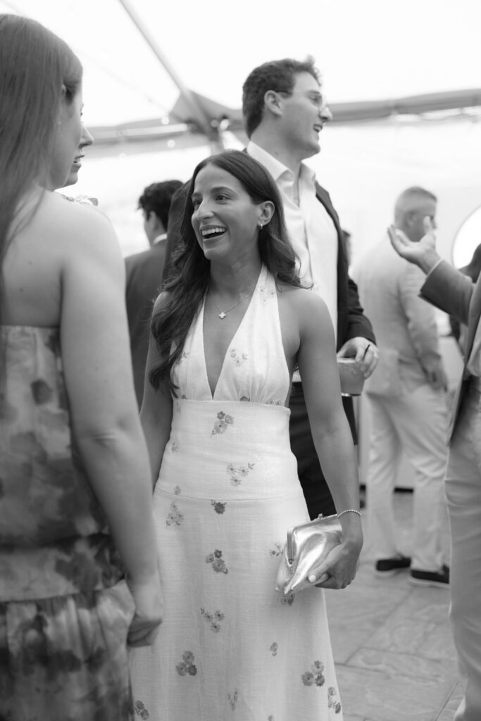 A woman laughs while talking to guests at a rehearsal dinner at Bridgehampton Tennis & Surf Club.