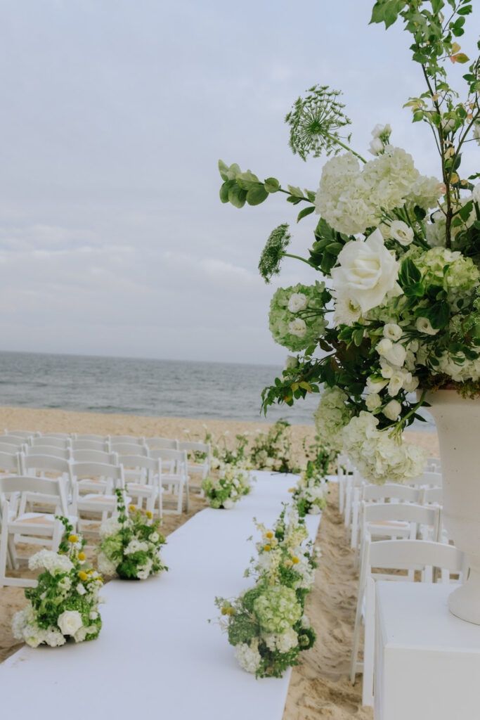 Beach wedding ceremony setup at Bridgehampton Tennis & Surf Club with white aisle runner and chairs.