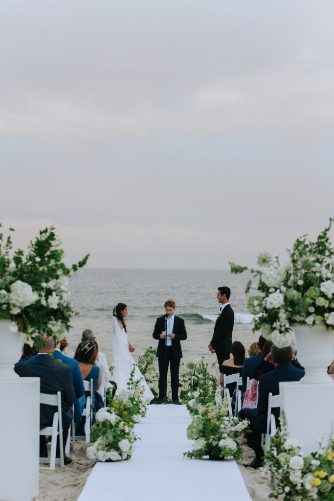 A couple exchanges vows on the beach during their Bridgehampton Tennis & Surf Club wedding.