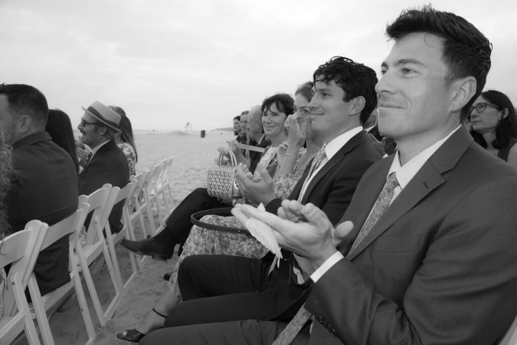 Guests applaud at a beach wedding ceremony at Bridgehampton Tennis & Surf Club in Bridgehampton, NY.