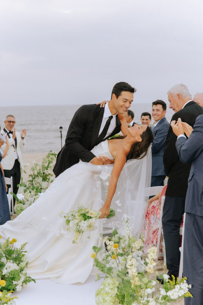 Groom dips the bride on the aisle at a Bridgehampton Tennis & Surf Club wedding.