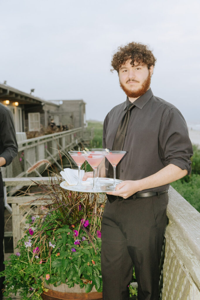 A server holds a tray of pink cocktails at a Bridgehampton Tennis & Surf Club wedding.