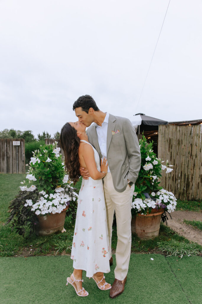 Couple kisses by potted plants at their Bridgehampton Tennis & Surf Club wedding.