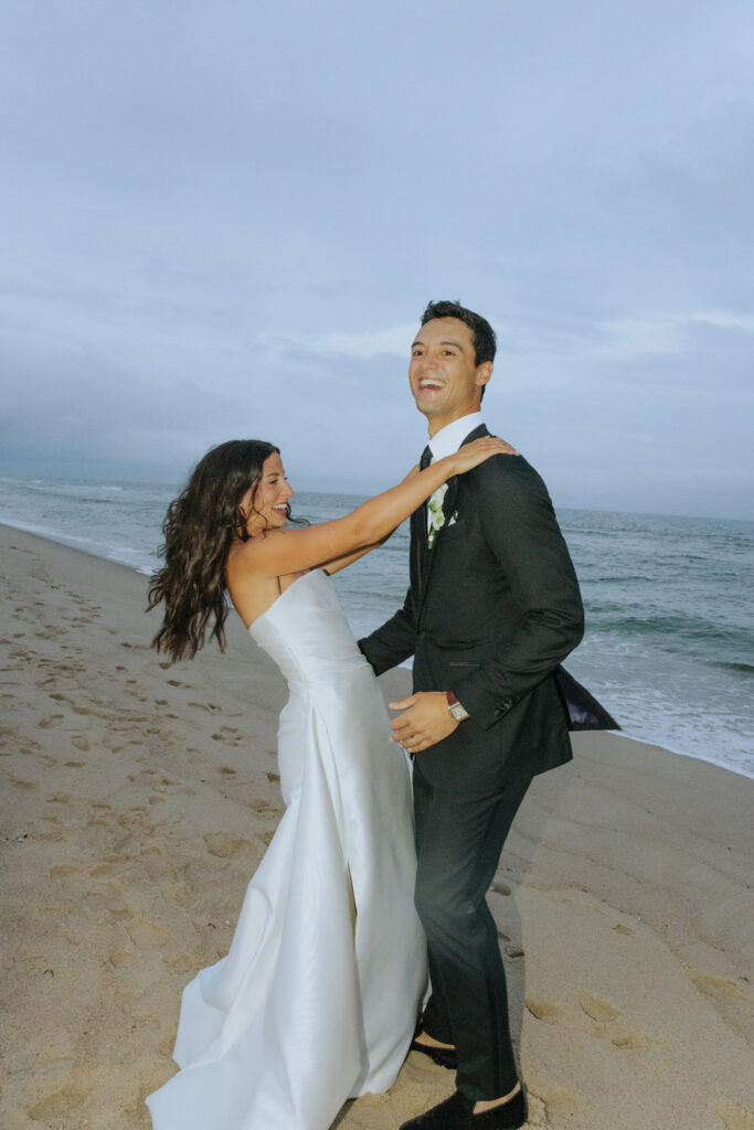Bride and groom standing on the sand by the ocean during a Bridgehampton Tennis & Surf Club wedding.