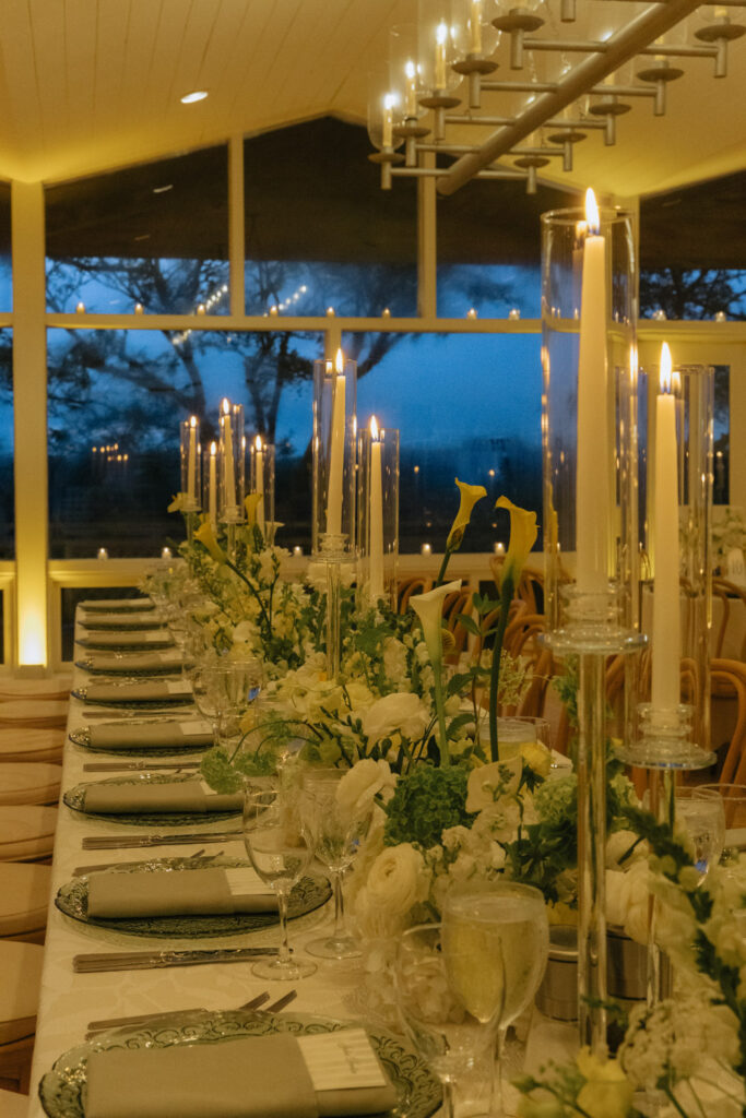 A long wedding reception table with candles and flowers at Bridgehampton Tennis & Surf Club.