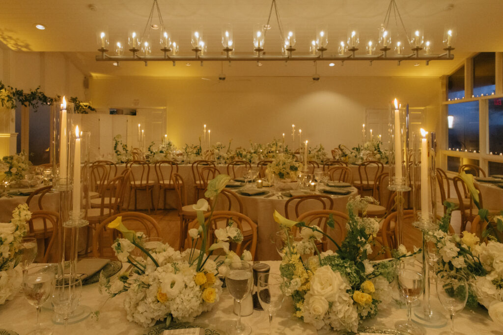 Candlelit reception tables with floral centerpieces at a Bridgehampton Tennis & Surf Club wedding.
