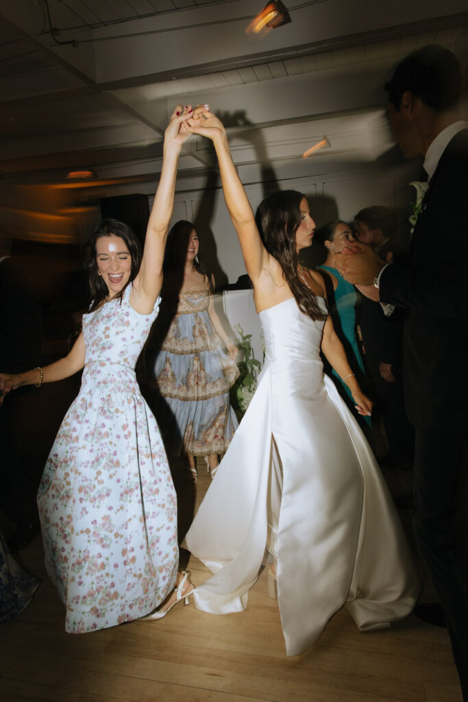 Wedding guests dance with arms raised at a Bridgehampton Tennis & Surf Club wedding reception.