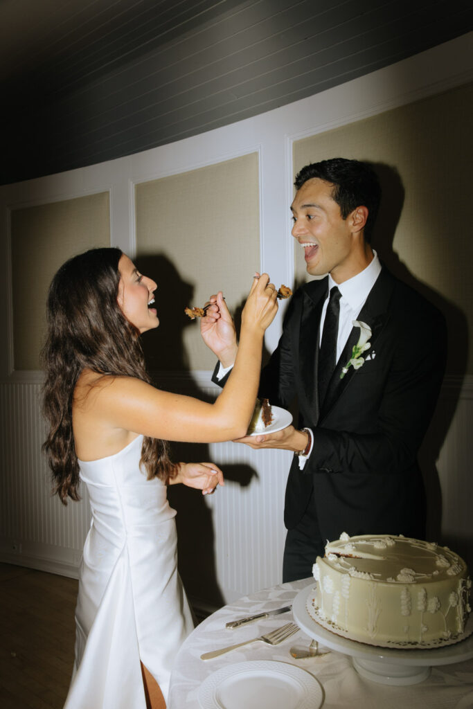Bride feeds groom cake at a Bridgehampton Tennis & Surf Club wedding on Long Island.