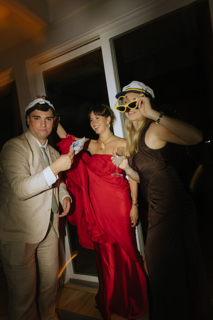 Wedding guests in party hats and dresses pose at a Bridgehampton Tennis & Surf Club wedding