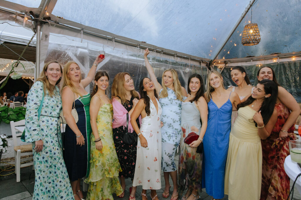 Group of women celebrating under a clear tent at a Bridgehampton Tennis & Surf Club wedding.