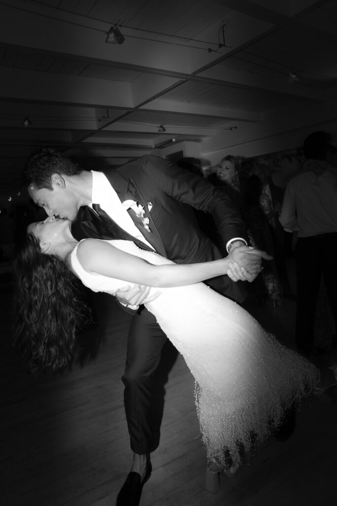 A groom dips and kisses his bride during their wedding reception at Bridgehampton Tennis & Surf Club.