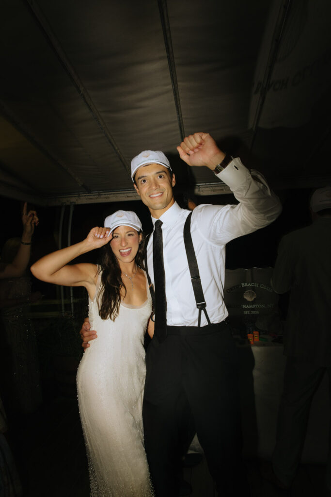 The couple celebrates with matching hats at their Bridgehampton Tennis & Surf Club wedding.