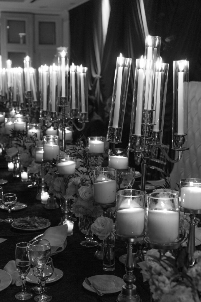 Candles and floral arrangements create centerpieces on tables during a wedding reception at Russos on the Bay.