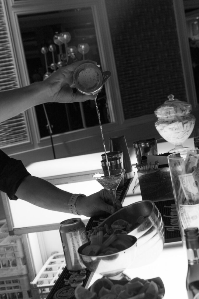 A person pouring a drink into a martini glass at a Russos on the Bay wedding reception.