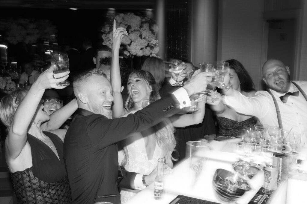 Wedding guests raise drinks and cheer at Russos on the Bay wedding in New York.
