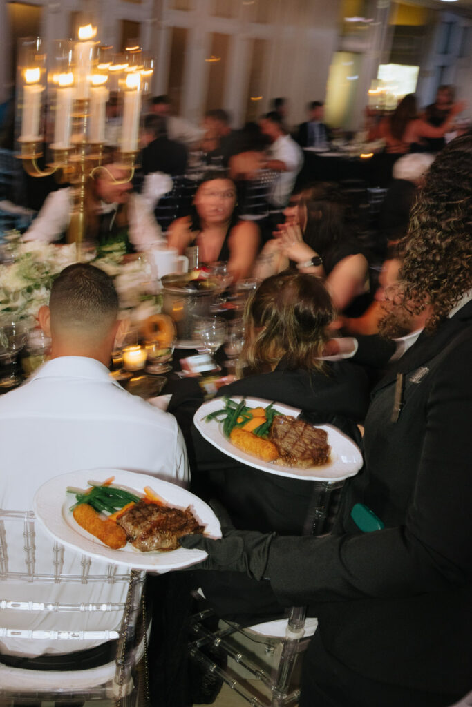 Servers deliver plated meals to guests at a wedding reception at Russos on the Bay.