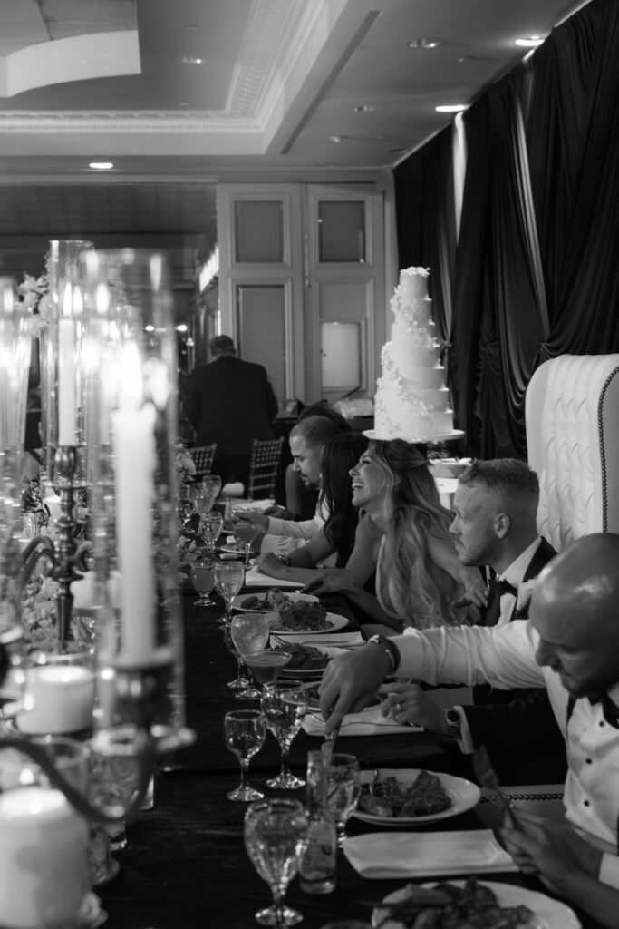 Wedding guests dining at a long table with candles and a large cake at Russos on the Bay.