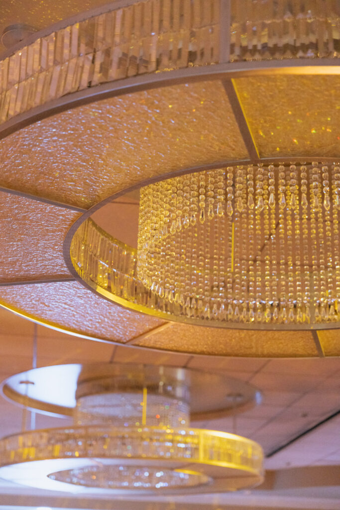 Close-up of sparkling chandeliers with golden elements at a Russos on the Bay wedding reception.