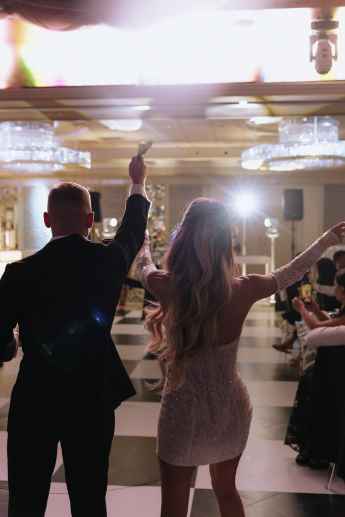 documentary wedding photographer captures A couple dances with their arms raised at a wedding reception at Russos on the Bay.