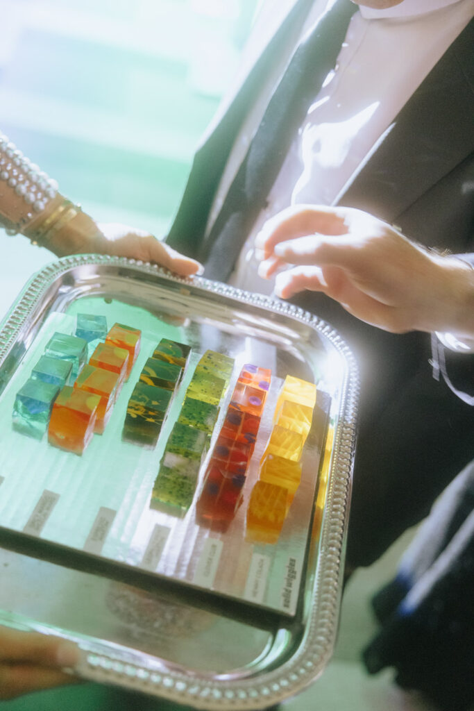 A server presents a tray of colorful dessert squares at a glamorous wedding at Russos on the Bay.