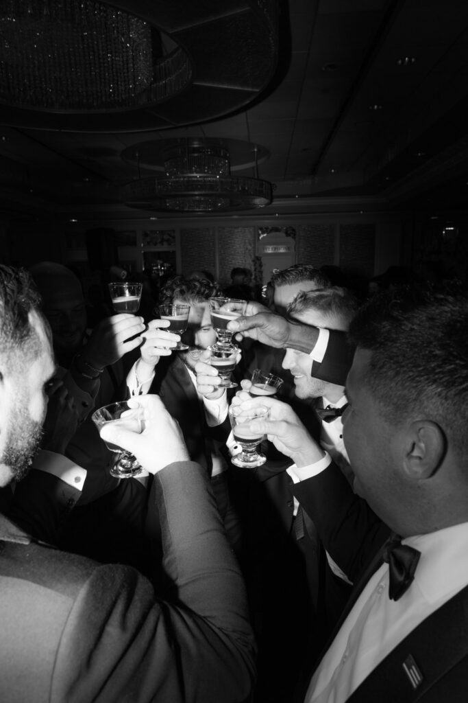 Men in tuxedos hold up glasses for a toast during a wedding at Russos on the Bay.