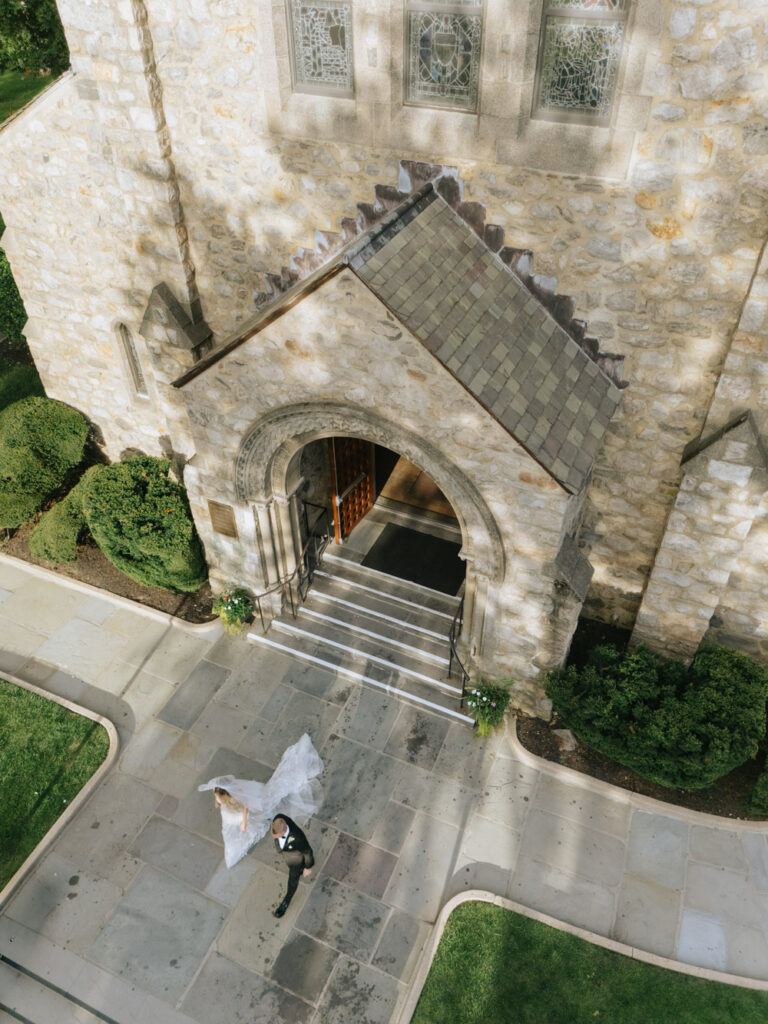 An aerial view of a bride and groom walking away from a Catholic ceremony at Russos on the Bay.