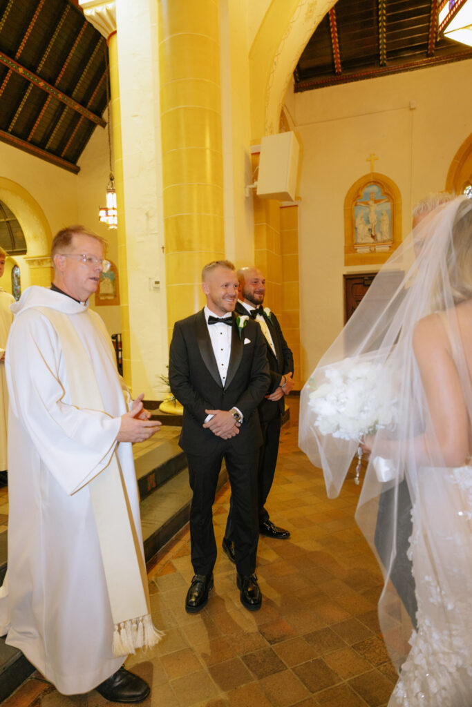 Groom smiles at his bride during their Catholic wedding ceremony at Russos on the Bay.