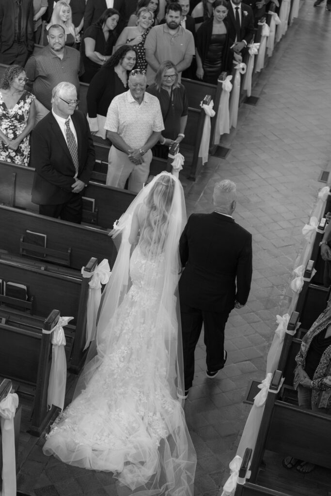A bride and groom walk down a church aisle at a Russos on the Bay wedding.