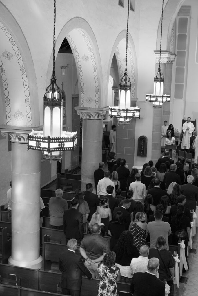 Wedding guests in pews watch a Catholic ceremony at Russos on the Bay.