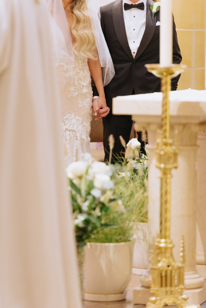 A bride and groom holding hands during their Catholic wedding ceremony at Russos on the Bay.