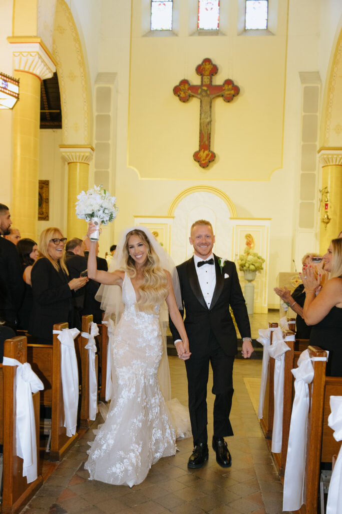 Newlyweds walking down the aisle in a Catholic ceremony at their Russos on the Bay Wedding.