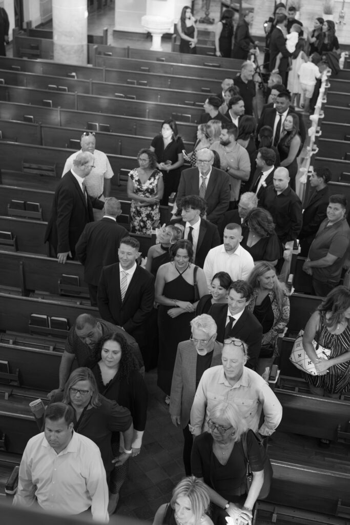 Wedding guests fill the pews of a Catholic church for a wedding ceremony at Russos on the Bay.