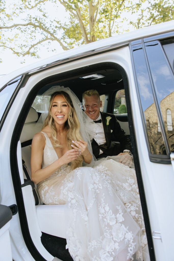 Bride and groom sitting in a white Rolls-Royce after their Catholic wedding ceremony at Russos on the Bay.