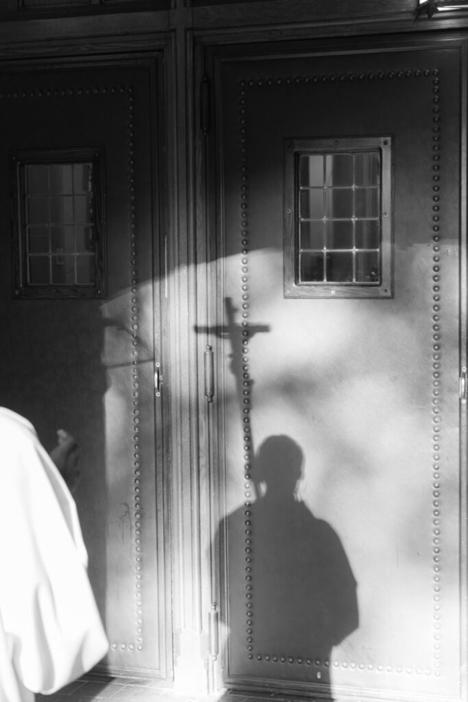 Shadows of a person and cross on a church door during a Catholic ceremony at Russos on the Bay.