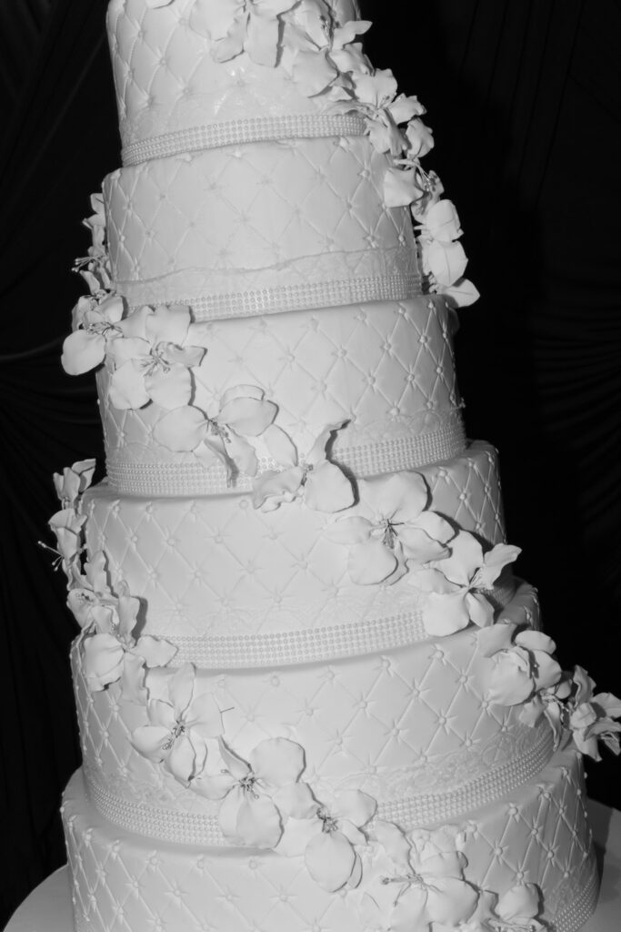 A multi-tiered wedding cake with white frosting and floral decorations at a Russos on the Bay wedding.