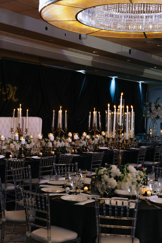 Tables set with black tablecloths, white floral arrangements, and candelabras at a Russos on the Bay wedding.