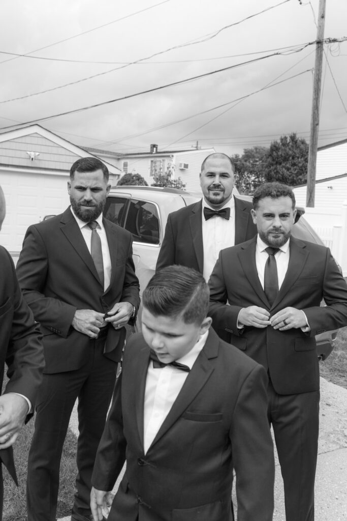 Men and a boy in suits adjusting their jackets at a Russos on the Bay wedding.
