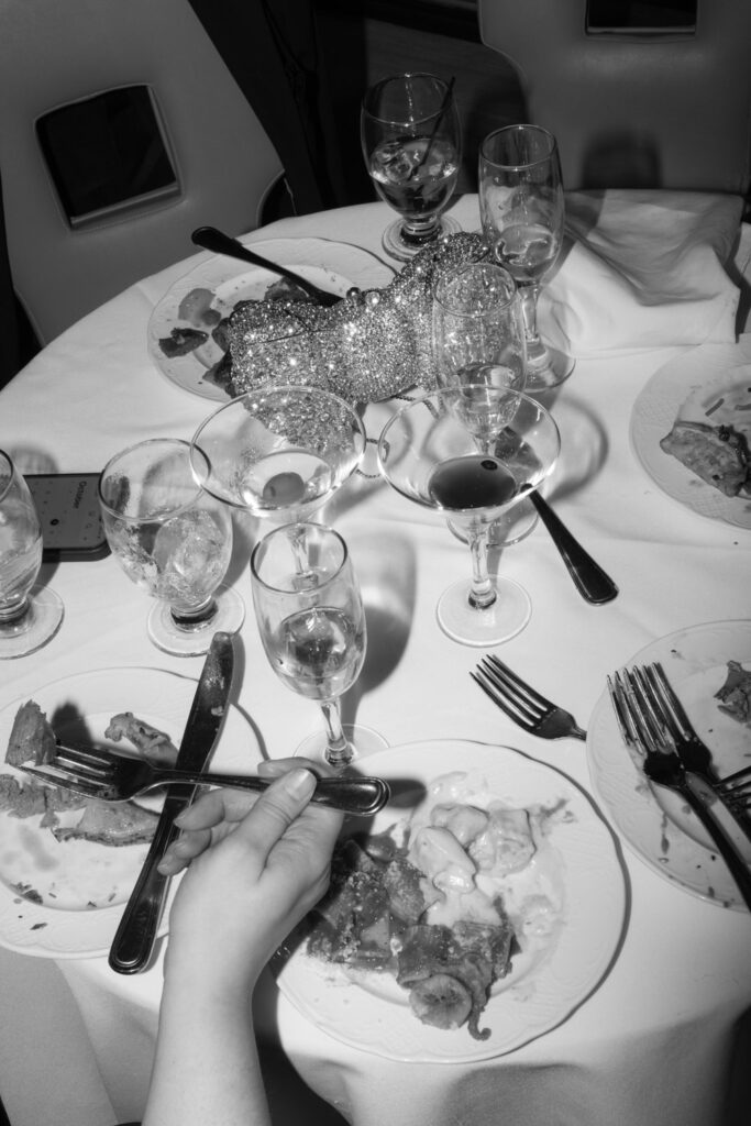 A guest holds silverware at a table with plates, glasses, and a glittery purse at a Russos on the Bay wedding.