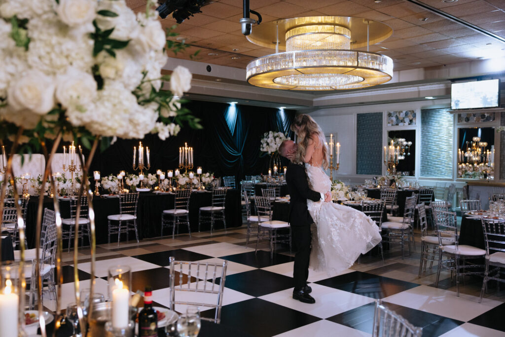 A groom holds his bride in a dip, kissing her, during a wedding at Russos on the Bay.