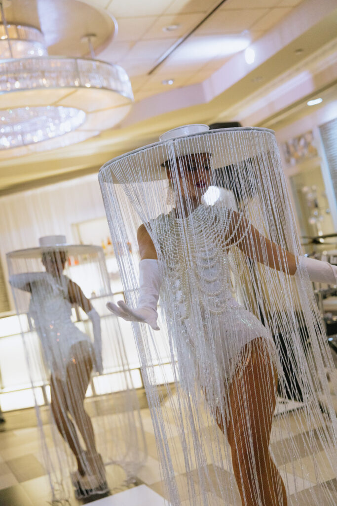 Two performers in white fringed cylindrical costumes with hats at a Russos on the Bay wedding reception.