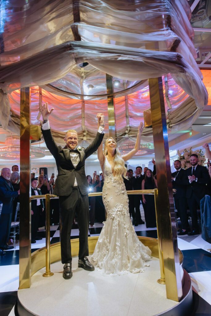 documentary wedding photographer captures A newlywed couple raises their arms in celebration during their grand entrance at a Russos on the Bay wedding.