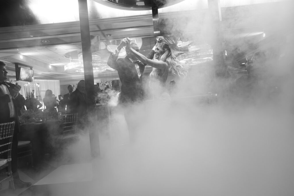 A bride and groom emerge from an elevator through smoke at their Russos on the Bay wedding.