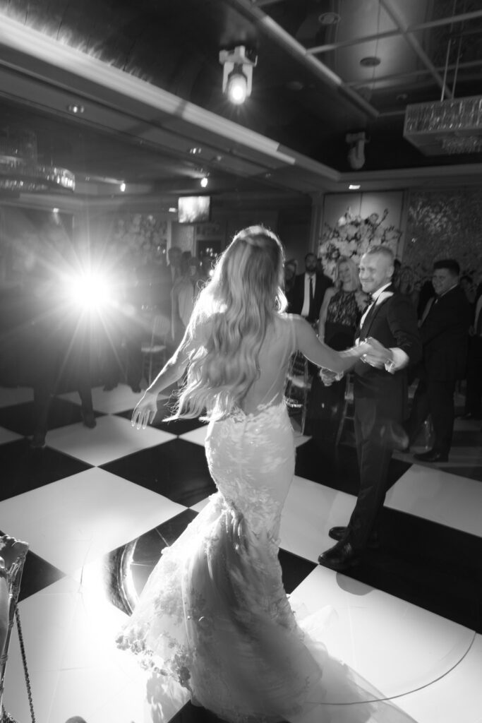 A bride and groom dancing on a black and white checkered floor at a Russo's on the Bay wedding.