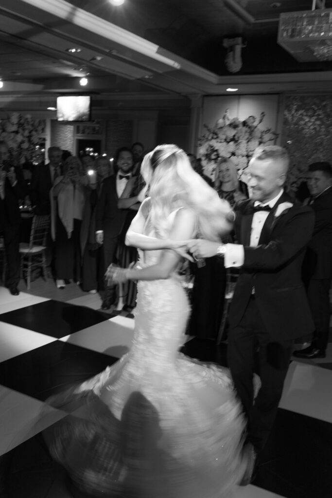 A bride and groom dance on a black and white checkered floor at a Russos on the Bay wedding.