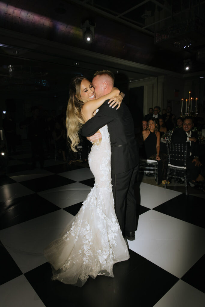 A newly married couple embraces on a black and white checkered dance floor at Russos on the Bay.