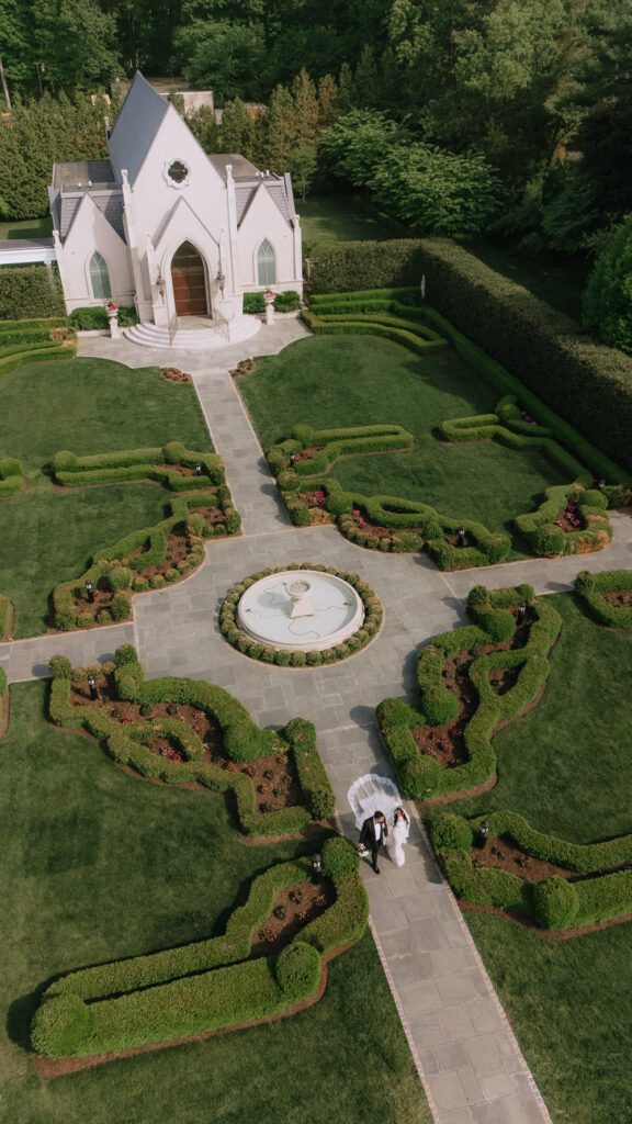A newlywed couple walks on a stone path through Park Chateau Estate & Gardens in New Brunswick, NJ.