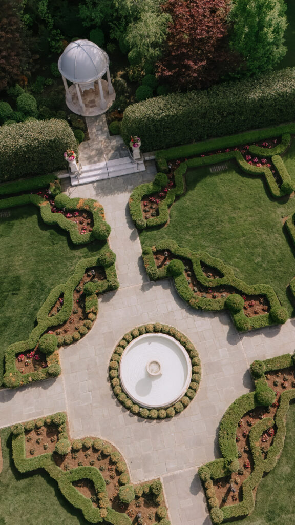 Aerial view of symmetrical formal gardens with a gazebo and circular fountain at Park Château.