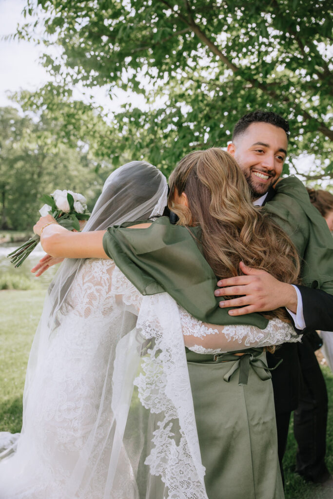 A man in a suit smiles while embracing two women at a Palestinian-Egyptian Muslim wedding at Park Chateau.