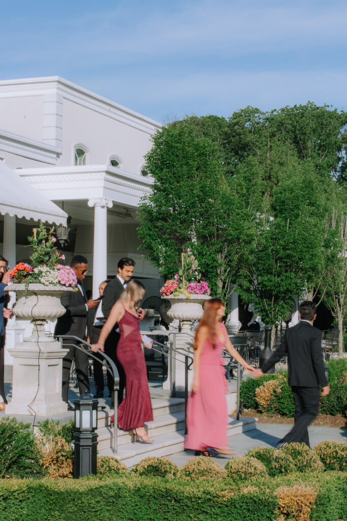Wedding guests in formal wear walk down outdoor steps at Park Chateau Estate & Gardens in East Brunswick, New Jersey.
