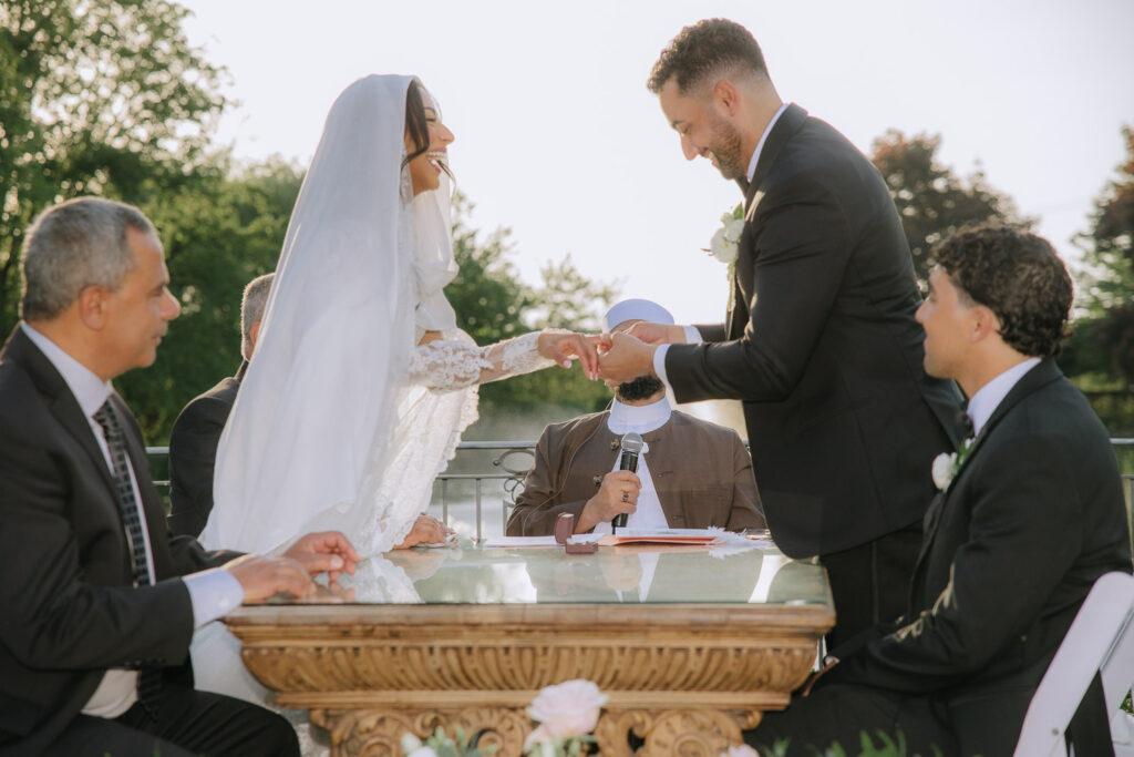A groom places a ring on the bride's finger during a Palestinian-Egyptian Muslim wedding at Park Chateau New Brunswick.